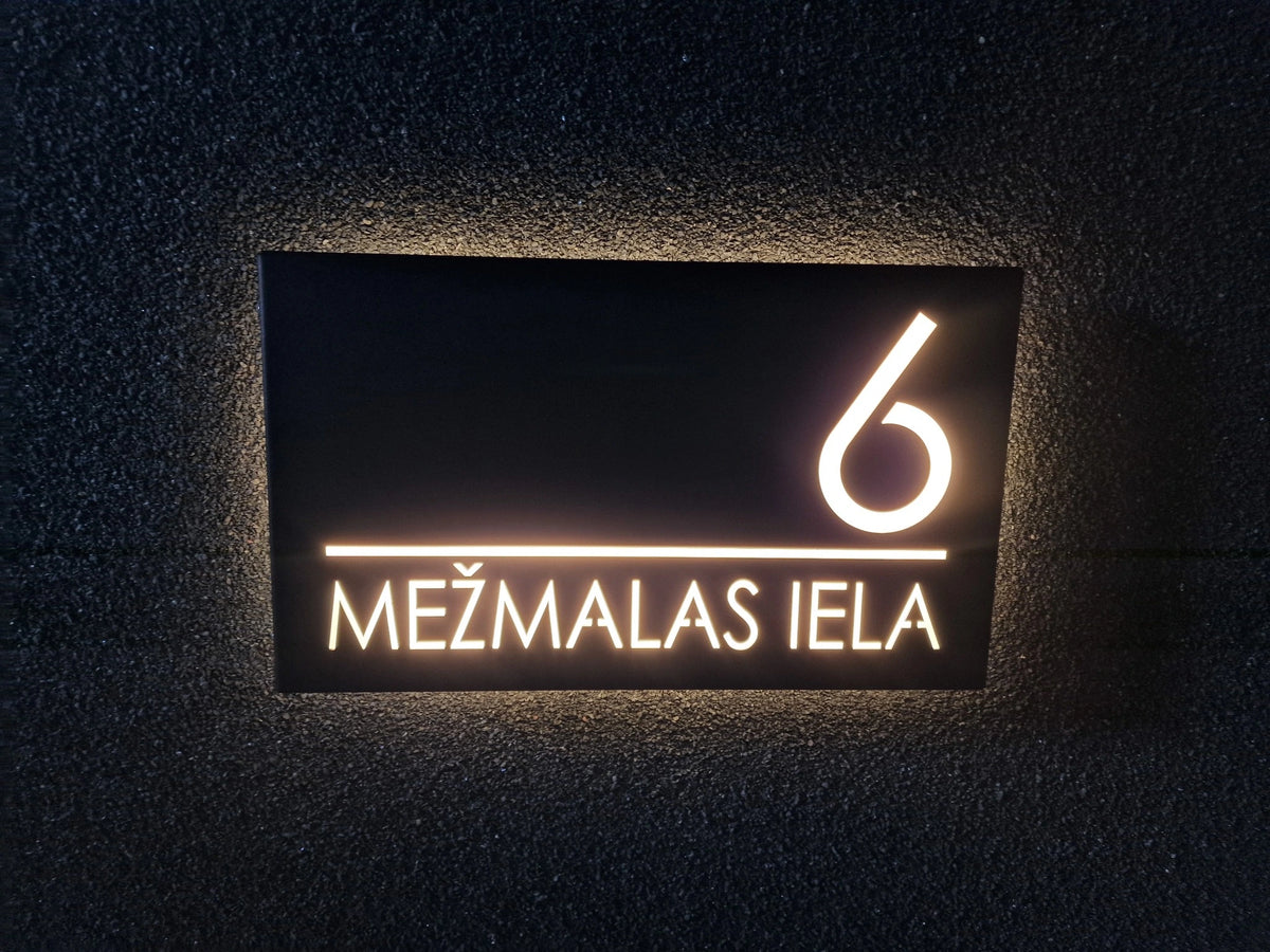 Front view of a black horizontal LumiSign Horizon on a dark rendered wall, with illuminated number 6, a divider and MEŽMALAS IELA lettering.