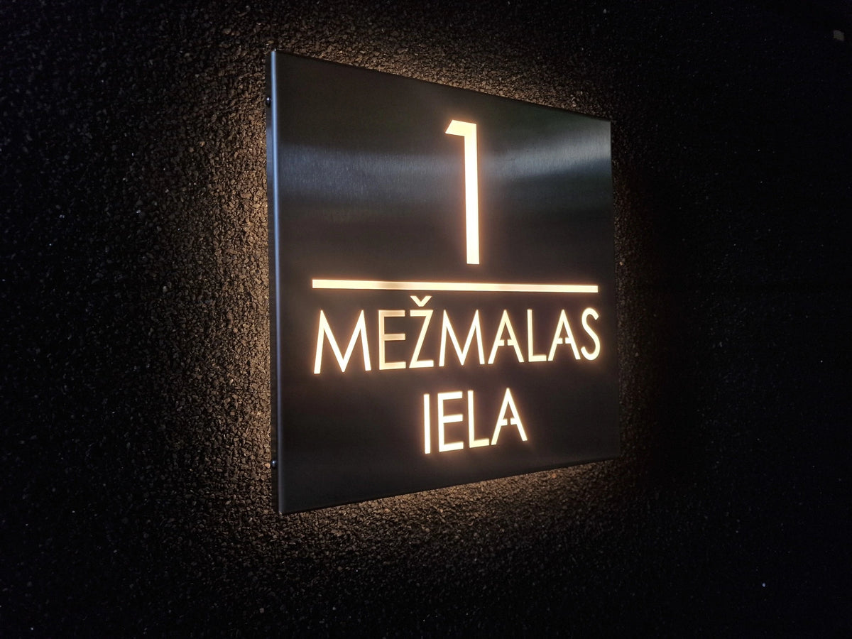 Stainless-steel square LumiSign with illuminated number 1 and two lines of street lettering, viewed at an angle on a dark rendered wall.